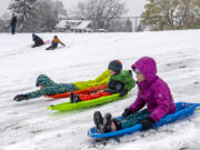 Emmaus Brownfield, 11, of Vancouver, left, races his siblings Alastair, 6, and Amira, 9, at the Franklin Elementary School sledding hill Monday.