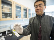 Feng Zhao, associate professor of electrical engineering at Washington State University Vancouver, holds up a glass slide containing silver electrodes and a thin film of honey on Wednesday at WSU Vancouver. Zhao and his students are trying to develop a honey-based neuromorphic computer chip that would be more energy efficient and environmentally friendly than current silicon-based chips.