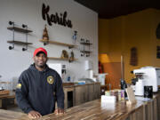 James Mbuya, owner of a new coffee shop in Uptown Village called Richland Hub, takes a break behind the front counter Friday morning. The "Karibu" sign behind him means "Welcome" in Swahili.