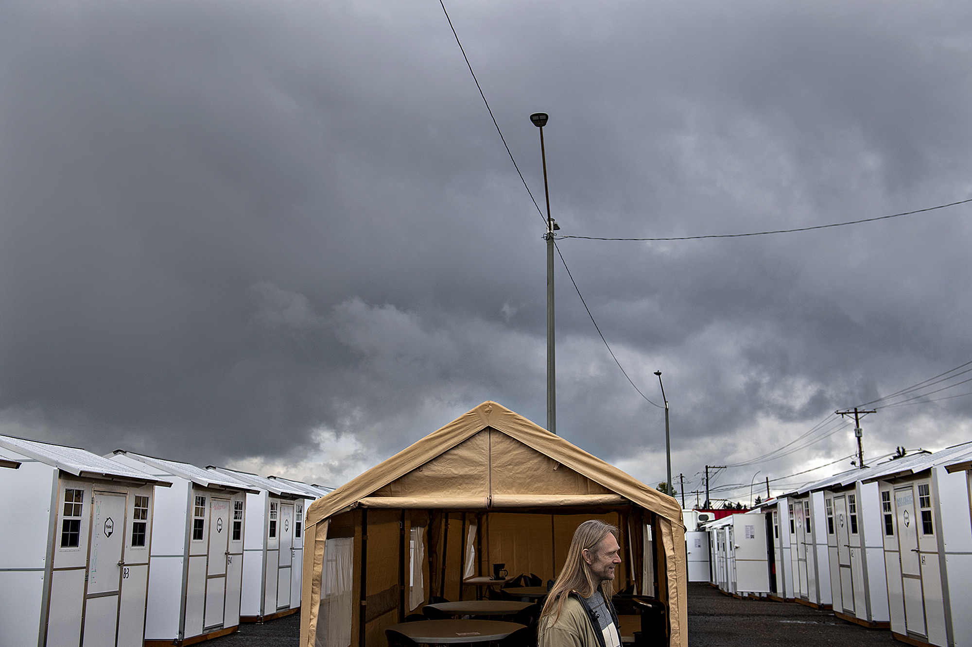 Storm clouds roll in as Charles Stuart, a future resident of Vancouver's Stay Safe Community, talks to the media about having the new housing option Wednesday morning, April 27, 2022. The units will provide shelter and a warm place to stay to those dealing with homelessness in addition to WiFi, running water, restrooms, a locking door and community space.