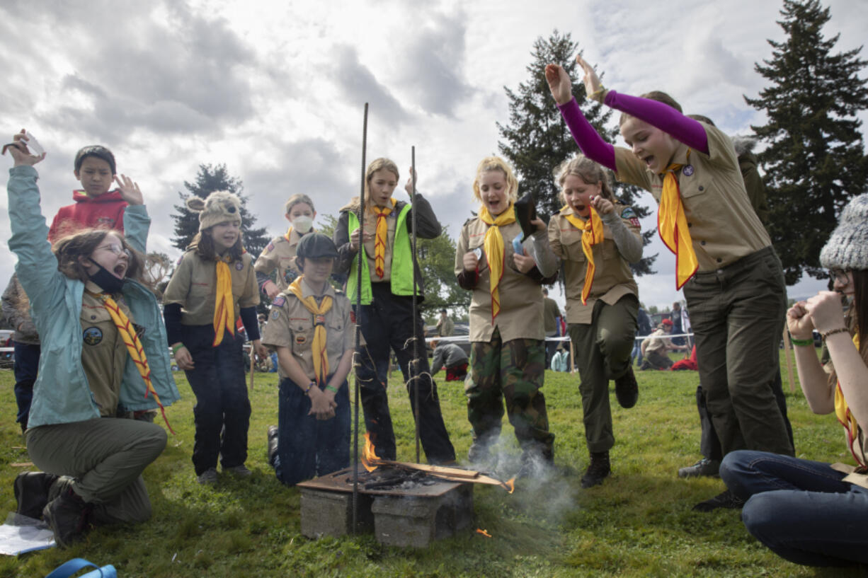 Members of Artemis Patrol Troop 351 from southeast Portland celebrate as the fire they built burns through all three strings in a fire-building challenge during Saturday's camporee at Fort Vancouver.