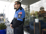 Security guard Austin MacMath wears a gun on his belt, Tuesday, April 19, 2022, while working outside Mary Mart, a marijuana store in Tacoma, Wash. A surge in robberies at licensed cannabis shops in Washington state is helping fuel a renewed push for federal banking reforms that would make the cash-dependent stores a less appealing target. (AP Photo/Ted S.