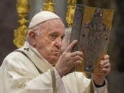 Pope Francis hoists the Gospel book during a Chrism Mass inside St. Peter's Basilica, at the Vatican, Thursday, April 14, 2022. During the mass the Pontiff blesses a token amount of oil that will be used to administer the sacraments for the year.