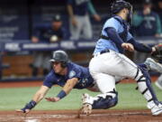 Seattle Mariners' Dylan Moore Dives to slides in behind Tampa Bay Rays catcher Mike Zunino to score during the fourth inning of a baseball game Tuesday, April 26, 2022, in St. Petersburg, Fla.