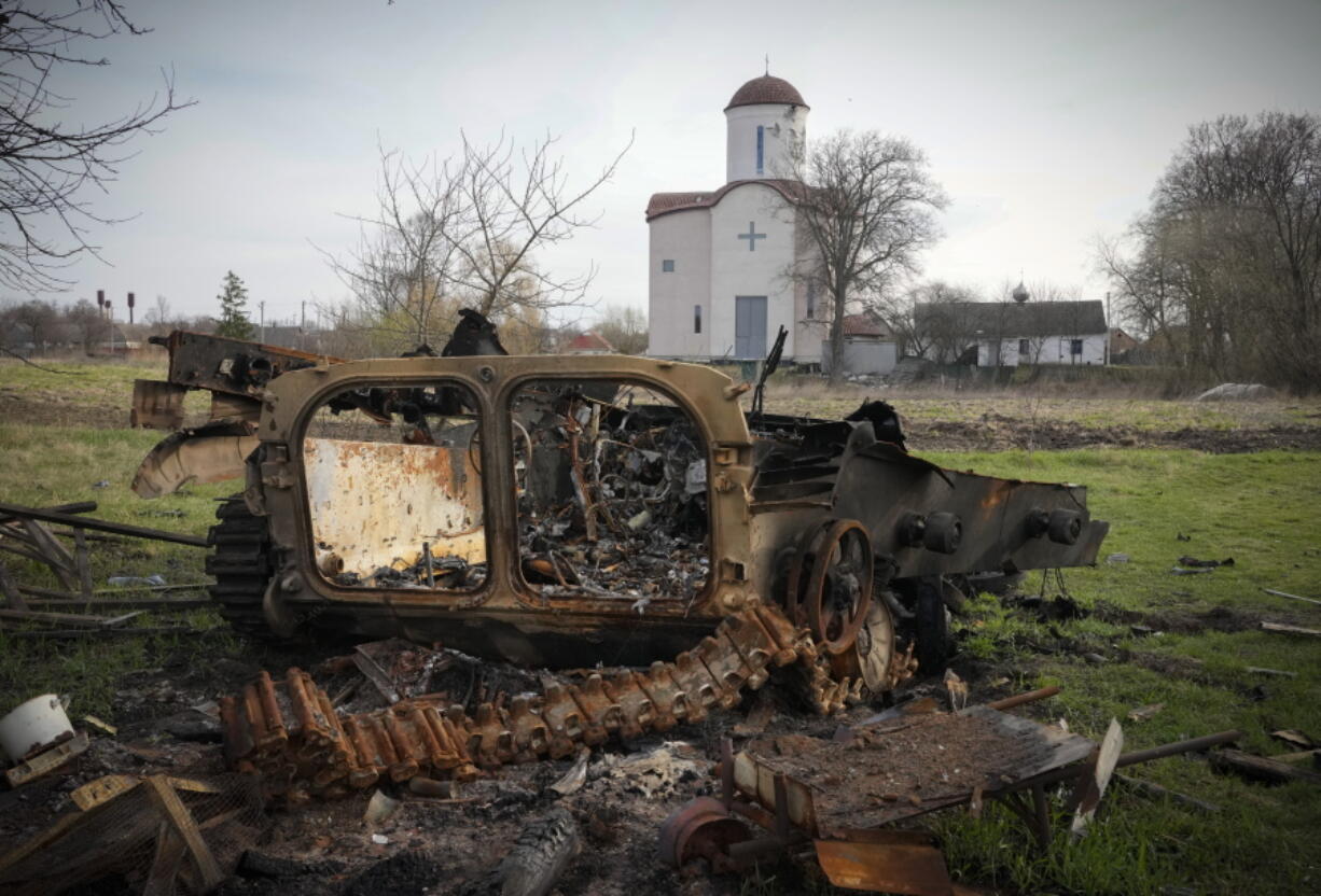 FILE - Fragments of a destroyed Russian military vehicle lie against the background of an Orthodox church in the village of Lypivka close to Kyiv, Ukraine, on April 11, 2022. Lypivka was occupied by the Russian troops at the beginning of the Russia-Ukraine war and freed recently by the Ukrainian army. Many Americans continue to question whether President Joe Biden is showing enough strength in response to Russia's war against Ukraine, even as most approve of steps the U.S. is already taking and few want U.S. troops to get involved in the conflict.