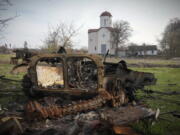 FILE - Fragments of a destroyed Russian military vehicle lie against the background of an Orthodox church in the village of Lypivka close to Kyiv, Ukraine, on April 11, 2022. Lypivka was occupied by the Russian troops at the beginning of the Russia-Ukraine war and freed recently by the Ukrainian army. Many Americans continue to question whether President Joe Biden is showing enough strength in response to Russia's war against Ukraine, even as most approve of steps the U.S. is already taking and few want U.S. troops to get involved in the conflict.