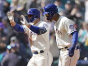 Seattle Mariners' Ty France left, reacts with Julio Rodriguez, right, after France hit a three-run home run to score Rodriguez and Adam Frazier during the fourth inning of a baseball game against the Houston Astros, Sunday, April 17, 2022, in Seattle. (AP Photo/Ted S.