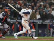 Seattle Mariners' Adam Frazier follows through on a single next to Houston Astros catcher Martin Maldonado during the sixth inning of a baseball game Friday, April 15, 2022, in Seattle. (AP Photo/Ted S.