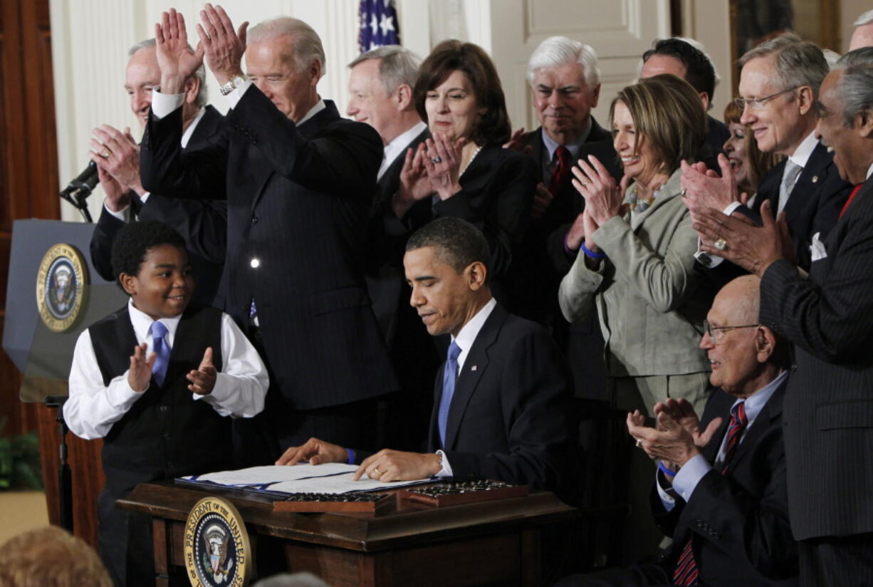 FILE -In this March 23, 2010, photo, President Barack Obama is applauded after signing the Affordable Care Act into law in the East Room of the White House in Washington. Obama returns to the White House on Tuesday, April 5, 2022, for a moment he can savor: His signature Affordable Care Act is now part of the fabric of the American health care system and President Joe Biden is looking to extend its reach.