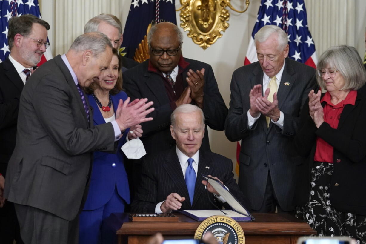 President Joe Biden signs the Postal Service Reform Act of 2022 in the State Dining Room at the White House in Washington, Wednesday, April 6, 2022. Watching from left are Sen. Gary Peters, D-Mich., Senate Majority Leader Chuck Schumer of N.Y., Sen. Rob Portman, R-Ohio, House Speaker Nancy Pelosi of Calif., Rep. James Clyburn, D-S.C., Rep. Steny Hoyer, D-Md., and Annette Taylor.