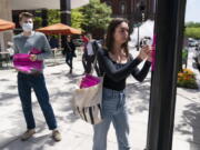 George Washington University student Kai Nilsen, left, watches as American University student Magnolia Mead as they put up posters near the White House promoting student loan debt forgiveness, Friday, April 29, 2022, in Washington.