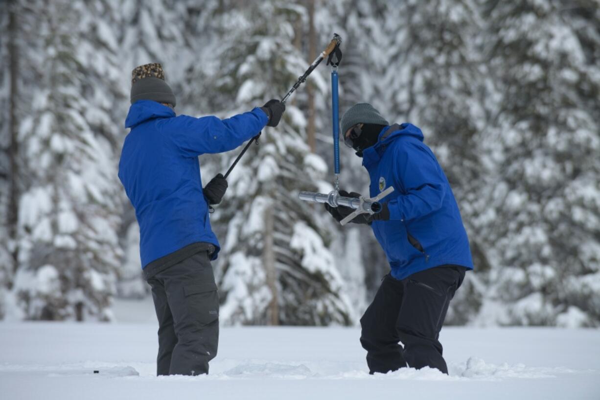 FILE -- Anthony Burdock, left, and Sean de Guzman, chief of snow surveys for the California Department of Water Resources, check the depth of the snow pack during the first snow survey of the season at Phillips Station near Echo Summit, Calif., Thursday, Dec. 30, 2021. Southern California's gigantic water supplier has taken the unprecedented step of requiring some 6 million people to cut their outdoor watering to one day a week as drought continues to plague the state.