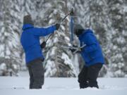 FILE -- Anthony Burdock, left, and Sean de Guzman, chief of snow surveys for the California Department of Water Resources, check the depth of the snow pack during the first snow survey of the season at Phillips Station near Echo Summit, Calif., Thursday, Dec. 30, 2021. Southern California's gigantic water supplier has taken the unprecedented step of requiring some 6 million people to cut their outdoor watering to one day a week as drought continues to plague the state.