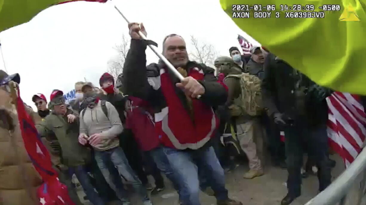 FILE - This still frame from Metropolitan Police Department body worn camera video shows Thomas Webster, in red jacket, at a barricade line at on the west front of the U.S. Capitol on Jan. 6, 2021, in Washington. Retired New York City police officer Webster is the next to go on trial, with jury selection scheduled to begin Monday, April 25, 2022. Webster has claimed he was acting in self-defense when he tackled a police officer who was trying to protect the Capitol from a mob on Jan. 6.