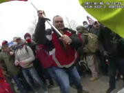 FILE - This still frame from Metropolitan Police Department body worn camera video shows Thomas Webster, in red jacket, at a barricade line at on the west front of the U.S. Capitol on Jan. 6, 2021, in Washington. Retired New York City police officer Webster is the next to go on trial, with jury selection scheduled to begin Monday, April 25, 2022. Webster has claimed he was acting in self-defense when he tackled a police officer who was trying to protect the Capitol from a mob on Jan. 6.