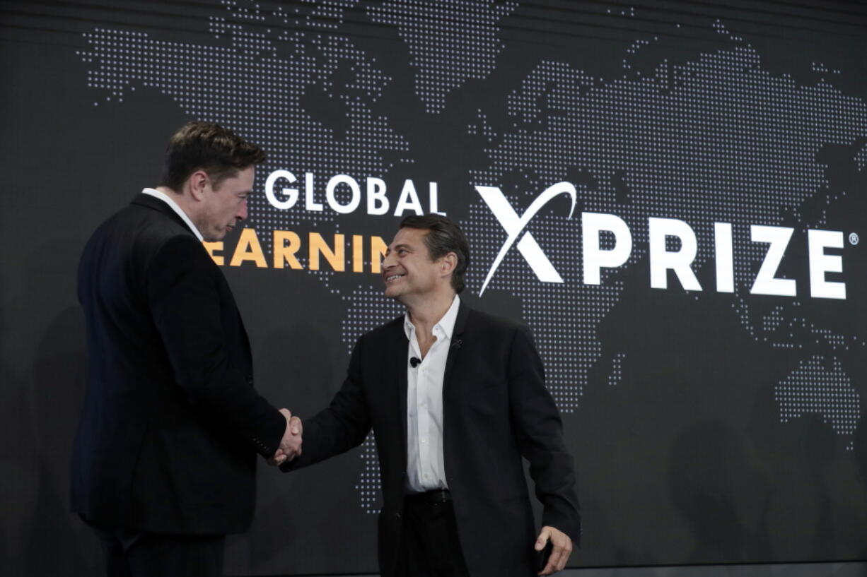 FILE - Tesla CEO Elon Musk, left, shakes hands with XPRIZE founder and Executive Chairman Peter Diamandis during an XPRIZE presentation event in Los Angeles, May 15, 2019. From algae farming to producing a sort of artificial limestone, ideas for reducing greenhouse gas in the atmosphere are getting a funding boost from famed entrepreneur Musk. The Tesla electric vehicle and SpaceX rocket company developer is bankrolling a $100 million XPRIZE Carbon Removal competition for the most promising ways to reduce atmospheric carbon dioxide by grabbing the gas right out of the air.