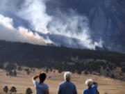 From left, Laura Tyson, Tod Smith and Rebecca Caldwell, residents of Eldorado Springs, watch as the NCAR fire burns in the foothills south of the National Center for Atmospheric Research, Saturday, March 26, 2022, in Boulder, Colo. The NCAR fire prompted evacuations in south Boulder and pre-evacuation warning for Eldorado Springs. According to a study published in Science Advances on Friday, April 1, 2022, a one-two punch of nasty wildfires followed by heavy downpours, triggering flooding and mudslides, will strike the U.S. West far more often in a warming-hopped world, becoming a frequent occurrence. (Helen H.