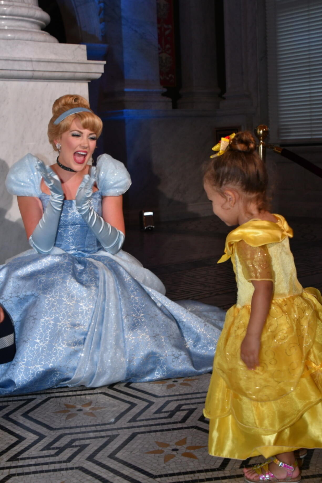 FILE - Costumed Cinderella greets a young guest at an event marking the inclusion of Disney's "Cinderella" into the National Film Registry on its 70th anniversary, June 20, 2019 at the Library of Congress in Washington. The costumed characters at the Disney parks in the U.S. have been back on the job for almost two years since the parks were temporarily shuttered due to the spread of the coronavirus. But there are a few things they haven't been able to do during that time: Give hugs, sign autographs and experience close-up interactions with visitors. That is about to change in a few weeks when the Disney parks re-introduce character greetings.