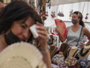 FILE - Women cool themselves with fans in the Rastro flea market during a heatwave in Madrid, Spain, Aug. 15, 2021. Scientists say last summer was the hottest summer on record in Europe, with temperatures a 1.8 Fahrenheit higher than the average for the previous three decades.