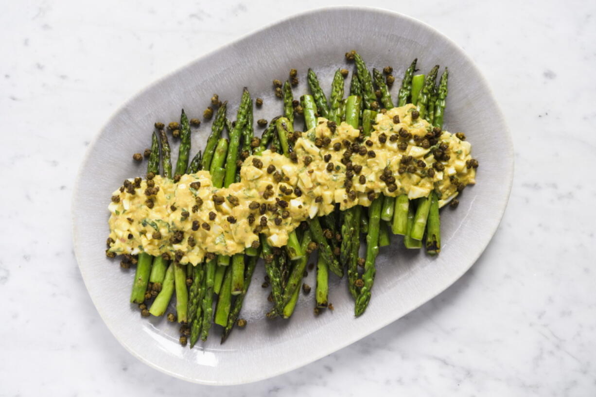 This image released by Milk Street shows a recipe for asparagus covered in Sauce gribiche and fried capers.