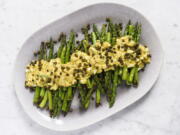 This image released by Milk Street shows a recipe for asparagus covered in Sauce gribiche and fried capers.