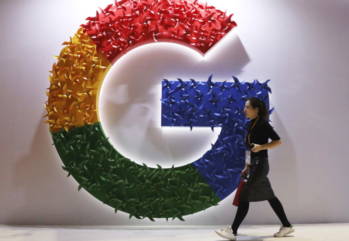 FILE - A woman walks past the logo for Google at the China International Import Expo in Shanghai on Nov. 5, 2018. Google said Friday, April 29, 2022 it will let people request that additional types of information such as personal contact information like phone numbers, email and physical addresses be removed from search results.