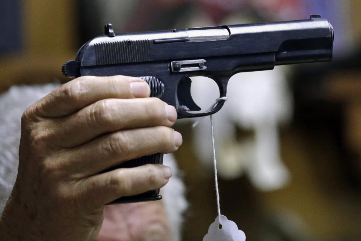 FILE - A sales clerk holds a pistol during an auction in Rochester, Wash., on Oct. 20, 2017. A study published in Annals of Internal Medicine on Monday, April 4, 2022, suggests people who live with handgun owners are murdered at more than twice the rate of people who live in homes without such firearms.