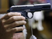 FILE - A sales clerk holds a pistol during an auction in Rochester, Wash., on Oct. 20, 2017. A study published in Annals of Internal Medicine on Monday, April 4, 2022, suggests people who live with handgun owners are murdered at more than twice the rate of people who live in homes without such firearms.