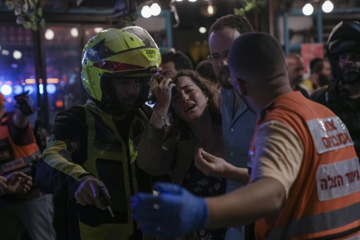 A woman reacts at the scene of a shooting attack In Tel Aviv, Israel, Thursday, April 7, 2022. Israeli health officials say two people were killed and at least eight others wounded in a shooting in central Tel Aviv. The shooting on Thursday evening, the fourth attack in recent weeks, occurred in a crowded area with several bars and restaurants. (AP Photo/Ariel Schalit).