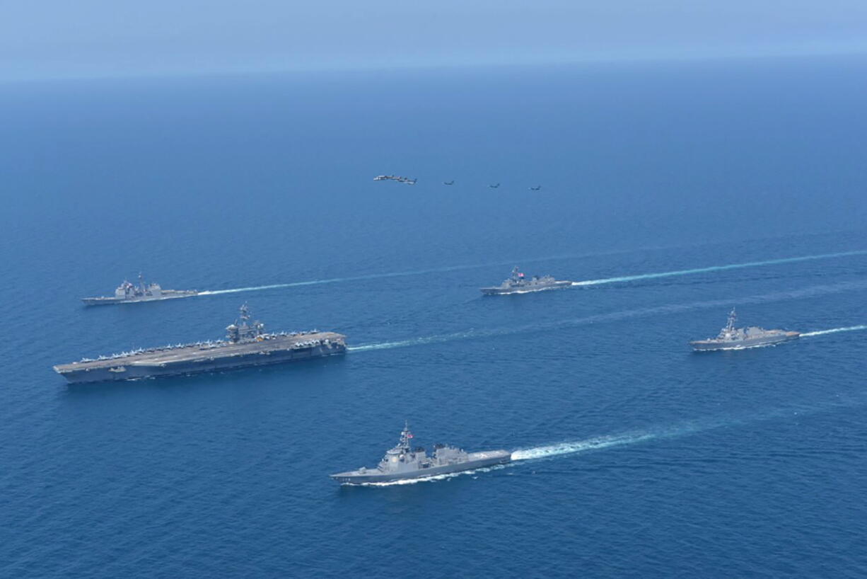 This photo provided by Japan Maritime Self-Defense Force shows USS Abraham Lincoln, left, and JS Kongo, front, sail in formation during a U.S.-Japan bilateral exercise at the Sea of Japan on April 12, 2022. U.S.