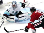 Seattle Kraken goaltender Philipp Grubauer, left, saves a shot by Chicago Blackhawks left wing Dominik Kubalik during the third period of an NHL hockey game in Chicago, Thursday, April 7, 2022. The Kraken won 2-0. (AP Photo/Nam Y.