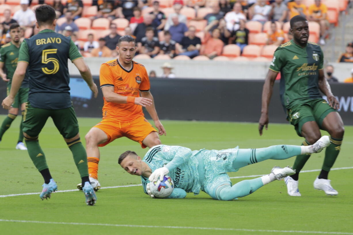 Portland Timbers goalkeeper Aljaz Ivacic, bottom, dives onto a shot on goal between, from left to right, defender Timbers' Claudio Bravo (5), Houston Dynamo forward Sebastian Ferreira (9) and Timbers defender Larrys Mabiala during the first half of an MLS soccer match Saturday, April 16, 2022, in Houston.