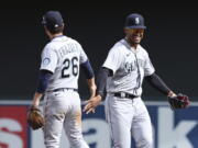 Seattle Mariners second baseman Adam Frazier (26) high fives teammate center fielder Julio Rodriguez in celebration after winning 4-3 against the Minnesota Twins after a baseball game Saturday, April 9, 2022, in Minneapolis.