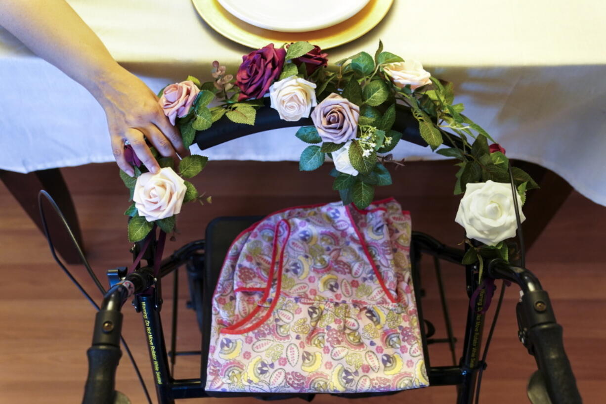 A woman holds the walker once belonging to her mother, who died of COVID-19 while at a nursing home, as her family prays before Thanksgiving dinner in 2020 in Deer Park, N.Y.