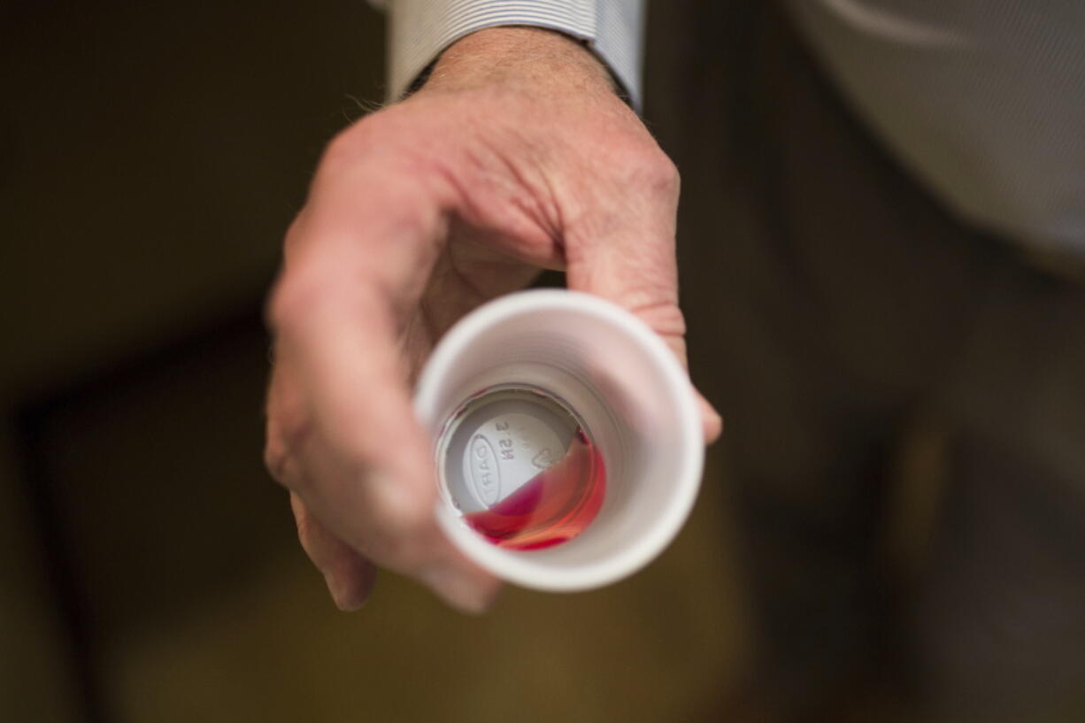 FILE - Paul "Rip" Connell, CEO of Private Clinic North, a methadone clinic, shows a 35 mg liquid dose of methadone at the clinic in Rossville, Ga., on March 7, 2017. A deepening opioid epidemic is prompting the U.S. Department of Justice to warn about discrimination against those who are taking medication to wean themselves off their addiction. In guidelines published Tuesday, April 5, 2022, the DOJ said employers, health care providers, jails and others cannot discriminate against people because they are taking prescribed drugs to treat opioid use disorder. (AP Photo/Kevin D.