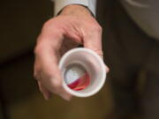 FILE - Paul "Rip" Connell, CEO of Private Clinic North, a methadone clinic, shows a 35 mg liquid dose of methadone at the clinic in Rossville, Ga., on March 7, 2017. A deepening opioid epidemic is prompting the U.S. Department of Justice to warn about discrimination against those who are taking medication to wean themselves off their addiction. In guidelines published Tuesday, April 5, 2022, the DOJ said employers, health care providers, jails and others cannot discriminate against people because they are taking prescribed drugs to treat opioid use disorder. (AP Photo/Kevin D.