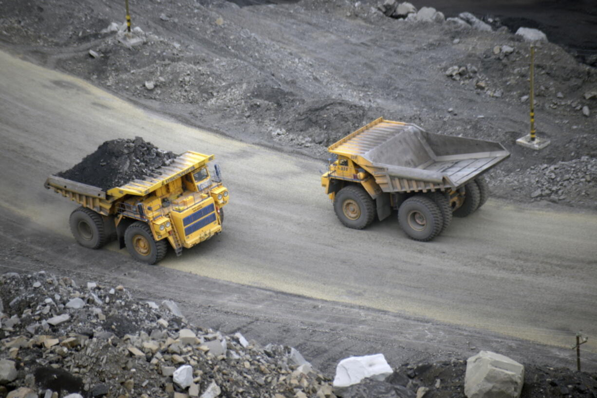 FILE - A loaded dump truck passes an empty truck as it carries away coal at the Kedrovsky open-pit coal mine in Kemerovo, Russia, Tuesday, June 16, 2015. Poland's government has decided to block imports of coal from Russia. The move is an element in a larger strategy to reduce energy dependence on Russia which gained new urgency after the invasion of Ukraine. The government of Prime Minister Mateusz Morawiecki agreed to impose financial penalties on the private entities importing Russian coal into Poland, with Polish customs officials tasked with carrying out checks. (AP Photo/Phelan M.