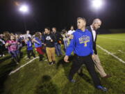 FILE - Bremerton High assistant football coach Joe Kennedy, front, walks off the field with his lawyer, right, Oct. 16, 2015, after praying at the 50-yard line following a football game in Bremerton, Wash. After losing his coaching job for refusing to stop kneeling in prayer with players and spectators on the field immediately after football games, Kennedy will take his arguments before the U.S. Supreme Court on Monday, April 25, 2022, saying the Bremerton School District violated his First Amendment rights by refusing to let him continue praying at midfield after games.