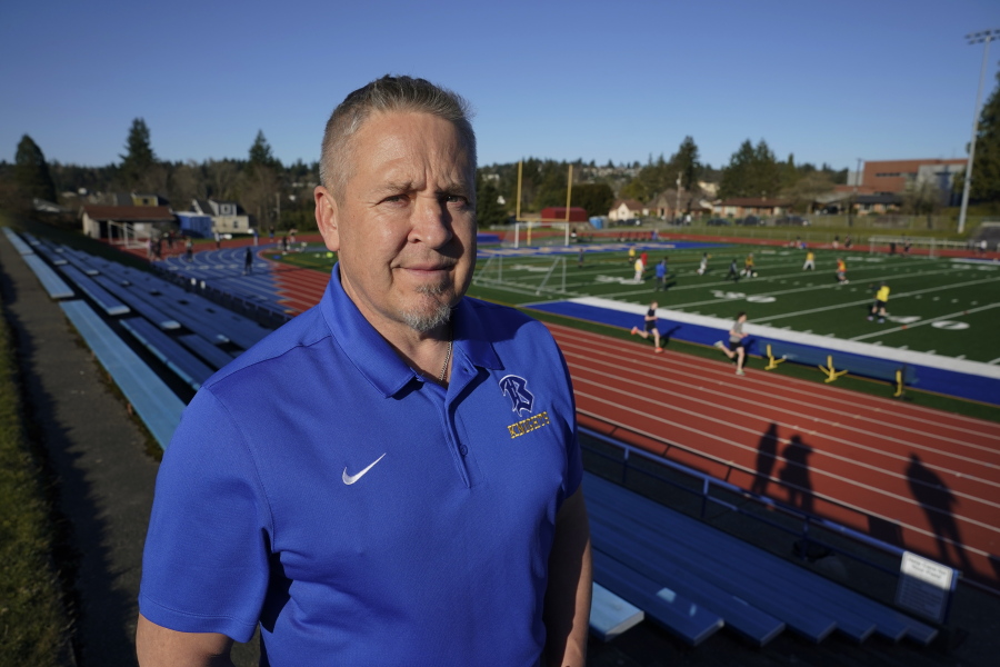 Joe Kennedy, a former assistant football coach at Bremerton High School in Bremerton, Wash., poses for a photo March 9, 2022, at the school's football field. After losing his coaching job for refusing to stop kneeling in prayer with players and spectators on the field immediately after football games, Kennedy will take his arguments before the U.S. Supreme Court on Monday, April 25, 2022, saying the Bremerton School District violated his First Amendment rights by refusing to let him continue praying at midfield after games. (AP Photo/Ted S.