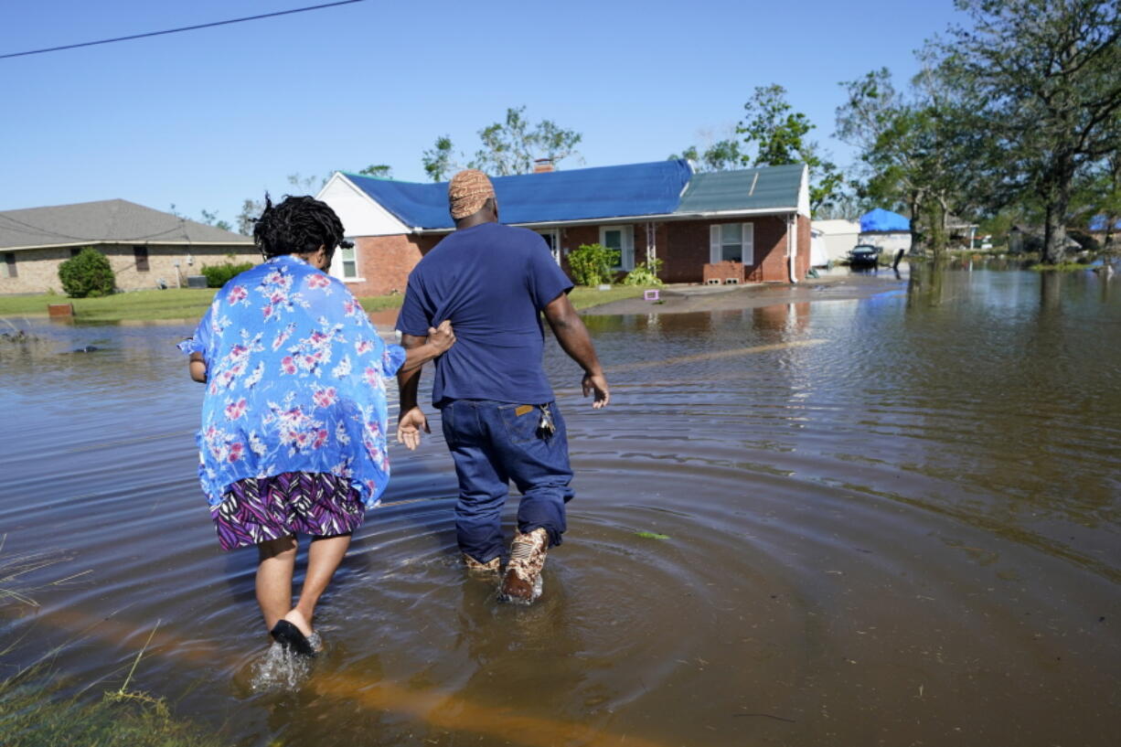 FILE - Soncia King holds onto her husband, Patrick King, in Lake Charles, La., Saturday, Oct. 10, 2020, as they walk through the flooded street to their home, after Hurricane Delta moved through the previous day. According to a study published in Nature Communications on Tuesday, April 12, 2022, climate change made the record-smashing deadly 2020 Atlantic hurricane season noticeably wetter.