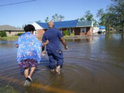 FILE - Soncia King holds onto her husband, Patrick King, in Lake Charles, La., Saturday, Oct. 10, 2020, as they walk through the flooded street to their home, after Hurricane Delta moved through the previous day. According to a study published in Nature Communications on Tuesday, April 12, 2022, climate change made the record-smashing deadly 2020 Atlantic hurricane season noticeably wetter.