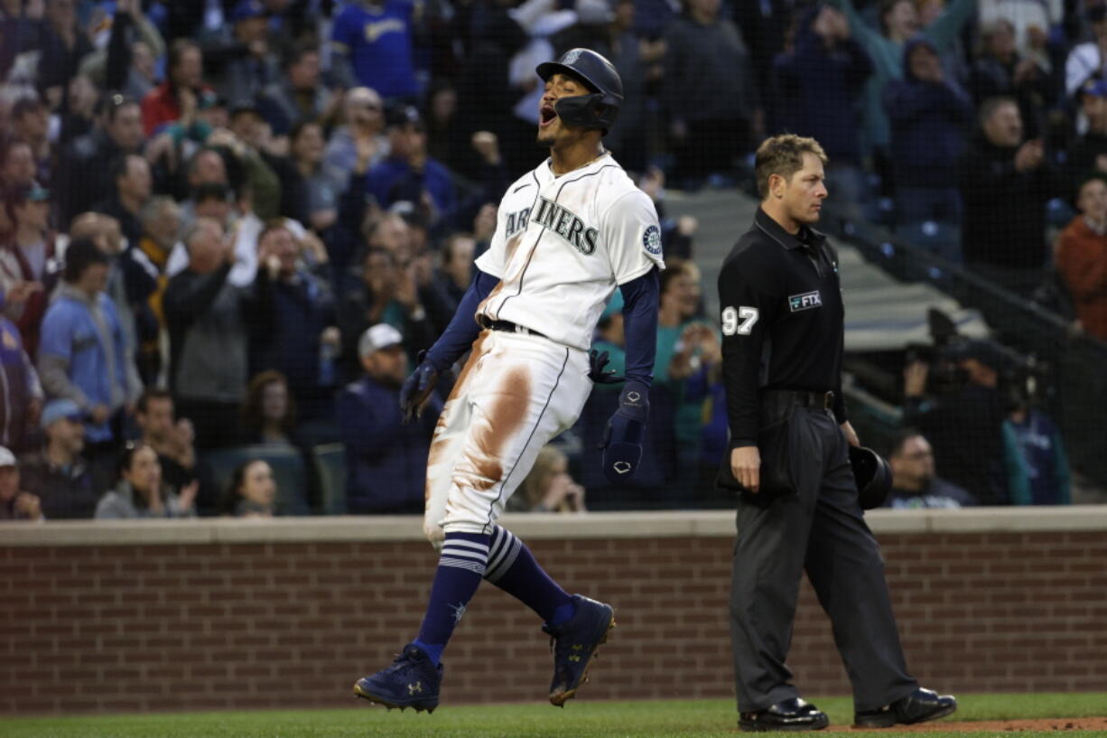 Seattle Mariners' Julio Rodriguez, left, reacts after scoring off a triple by Jarred Kelenic during the fourth inning of a baseball game against the Kansas City Royals, Friday, April 22, 2022, in Seattle.