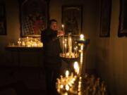 A man lights a candle during a Sunday service in an Orthodox church in Bucha, in the outskirts of Kyiv, Ukraine, Sunday, April 10, 2022.