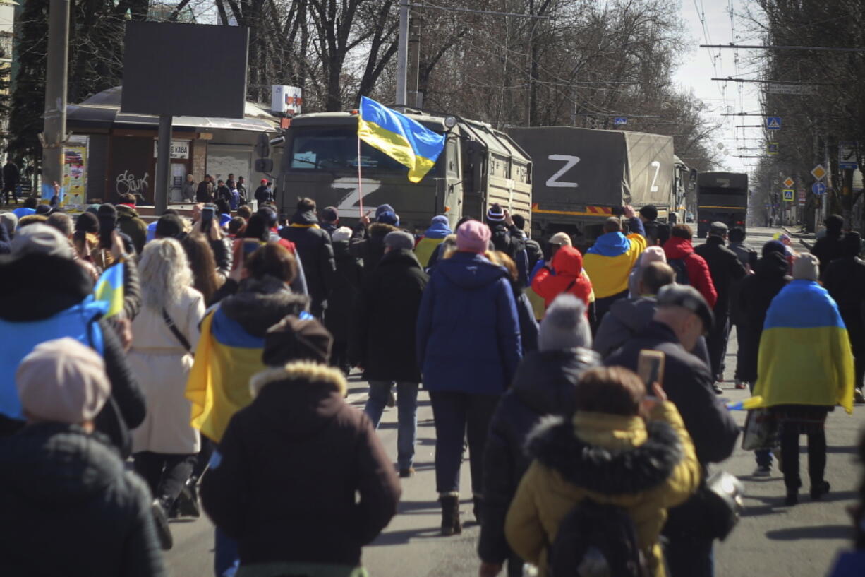 People with Ukrainian flags walk towards Russian army trucks during a rally against the Russian occupation in Kherson, Ukraine, Sunday, March 20, 2022. Ever since Russian forces took the southern Ukrainian city of Kherson in early March, residents sensed the occupiers had a special plan for their town. Now, amid a crescendo of warnings from Ukraine that Russia plans to stage a sham referendum to transform the territory into a pro-Moscow "people's republic," it appears locals guessed right.