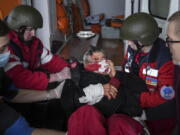 FILE - Ambulance paramedics move a civilian wounded in shelling onto a stretcher to a maternity hospital converted into a medical ward in Mariupol, Ukraine, March 2, 2022. A bipartisan group of U.S.