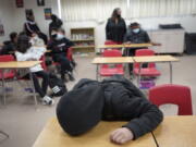 An unidentified student rests on his desk as the Mojave Unified School District Superintendent Katherine Aguirre, center rear, addresses students before their spring break at California City Middle School in California City, Calif., on Friday, March 11, 2022. Since the pandemic started, experts have warned of a mental health crisis facing American children that is now visibly playing out at schools across the country.