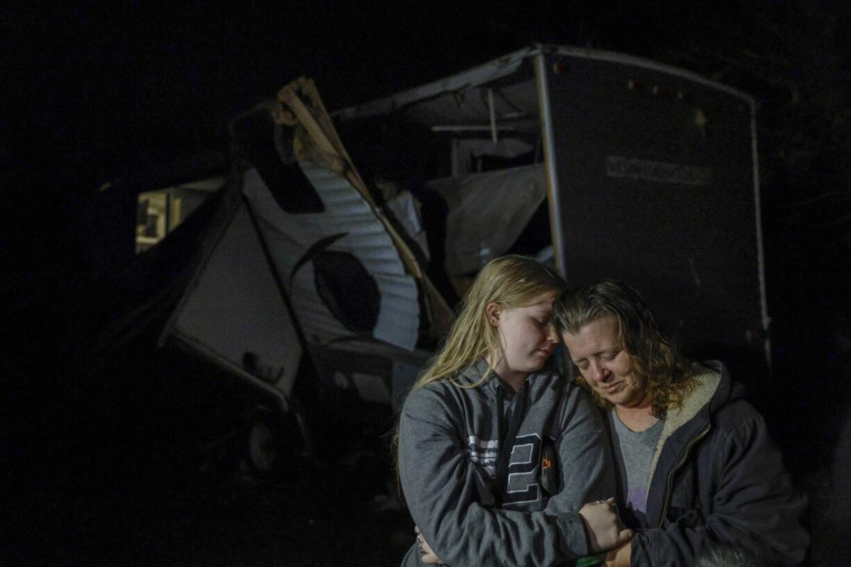 Brittaney Deaton, 17, left, comforts her mother Amber Zeleny, 53, while speaking with reporters after a severe storm passed in Johnson County near Burleson, Texas, Tuesday, April 5, 2022.  The latest round of storms to pound the South prompted a flurry of tornado warnings at the start of what forecasters said could be two days of violent weather in the region. More than 55,000 homes and businesses were without power Tuesday morning from eastern Texas to southern Mississippi after storms.