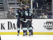 Seattle Kraken center Alex Wennberg, left and defenseman Carson Soucy (28) embrace left wing Jared McCann after he scored against the Dallas Stars during the first period of an NHL hockey game Sunday, April 3, 2022, in Seattle.