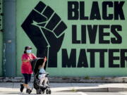 FILE - A girl in a stroller plays with a squirt gun as a woman pushes her past a Black Lives Matter mural in the Shaw neighborhood in Washington, Monday, July 13, 2020. The National Urban League released its annual report on the State of Black America on Tuesday, April 12, 2022, and its findings are grim. This year's Equality Index shows Black people still get only 73.9 percent of the American pie white people enjoy.