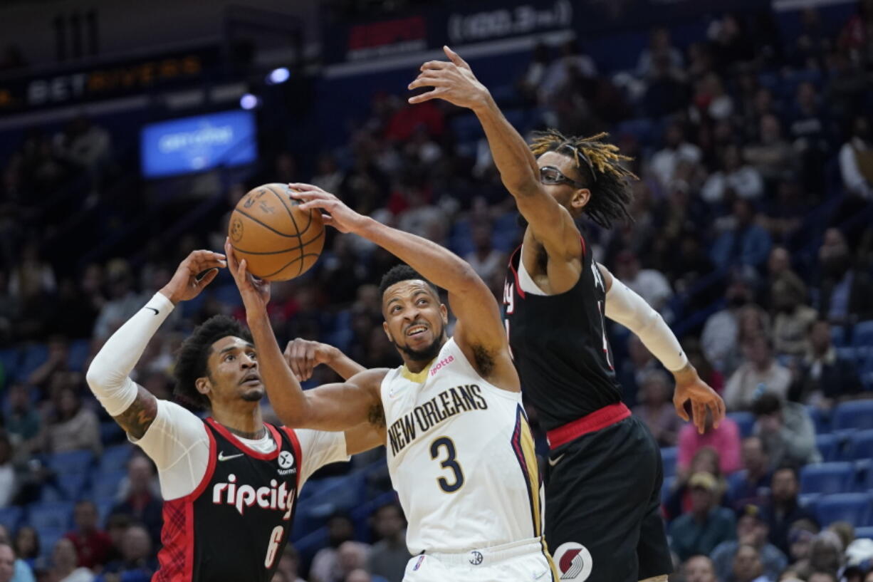 New Orleans Pelicans guard CJ McCollum (3) goes to the basket between Portland Trail Blazers guard Keon Johnson (6) and forward Greg Brown III in the second half of an NBA basketball game in New Orleans, Thursday, April 7, 2022.